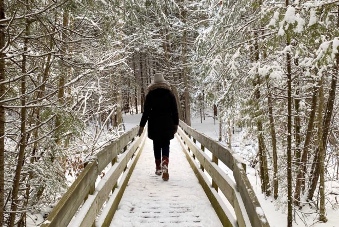 A person walking along a snowy boardwalk at H.R. Frink Conservation Area in the winter